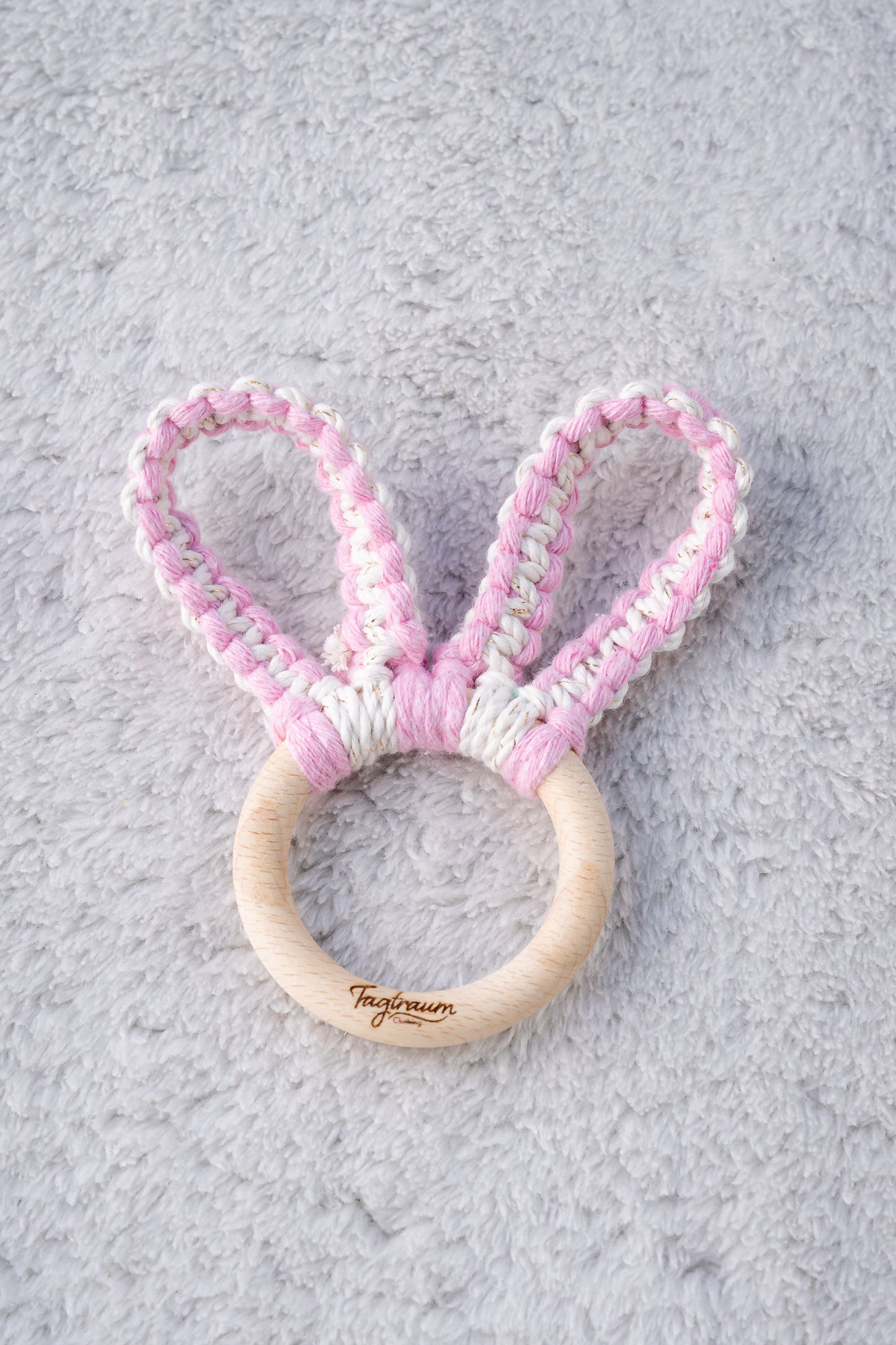Süsser Hasenohren Greifling für Babys aus einem schönen Holzring mit edler Tagtraum Gravur und Hasenöhrchen geknüpft aus Makrameegarn in süssem Rosa und Ecru mit Gold. Handgeknüpft von Tagtraum Clothing in der Schweiz