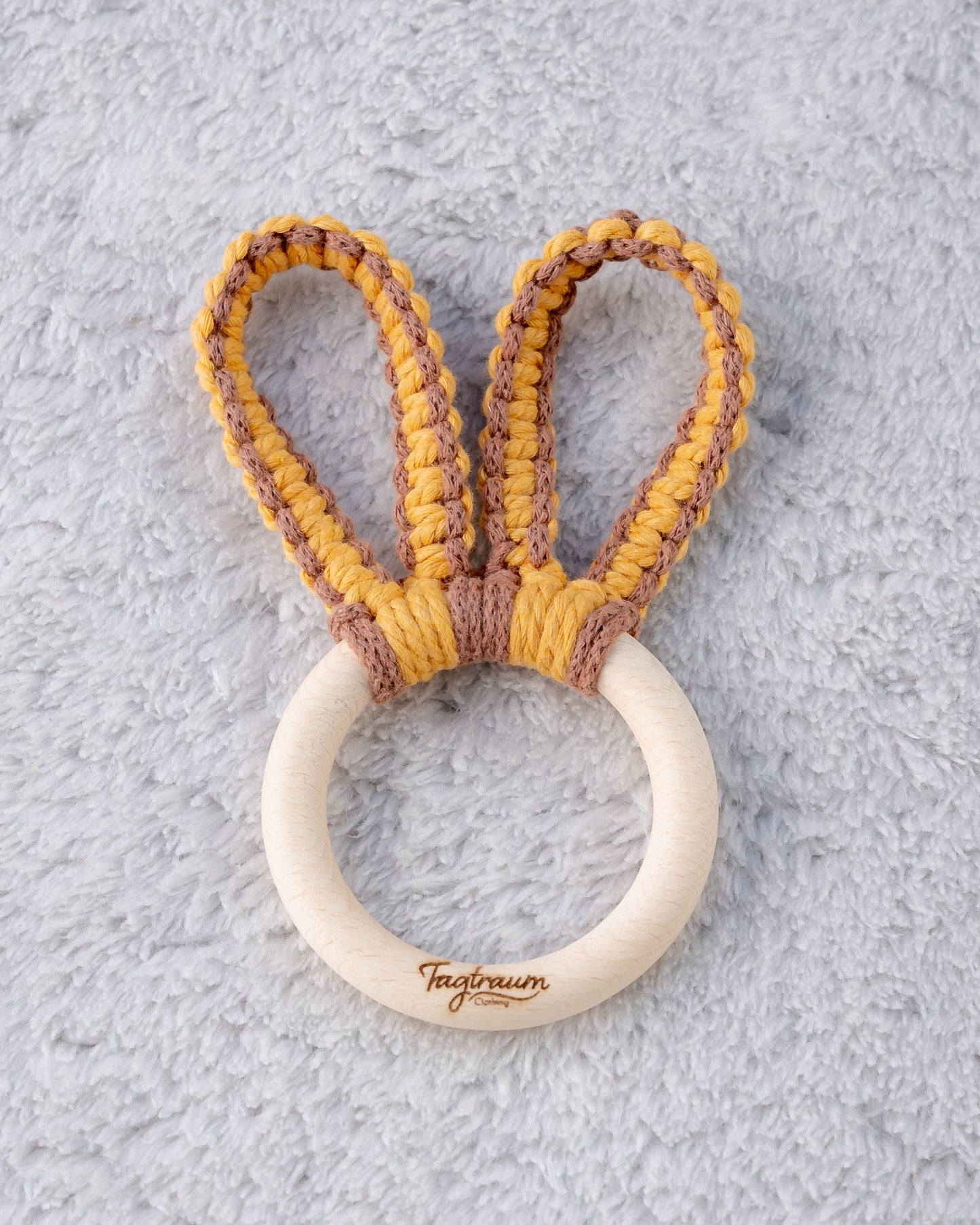 Süsser Greifling für Babys, aus einem schönen Holzring mit elder Tagtraum Gravur und süssen Hasenohren geknüpft aus Makramee Garn in sonnigem Gelb und schönem Braun. Frei von Schadstoffen und umweltfreundlich. Handgefertigt von Tagtraum Clothing in der Schweiz