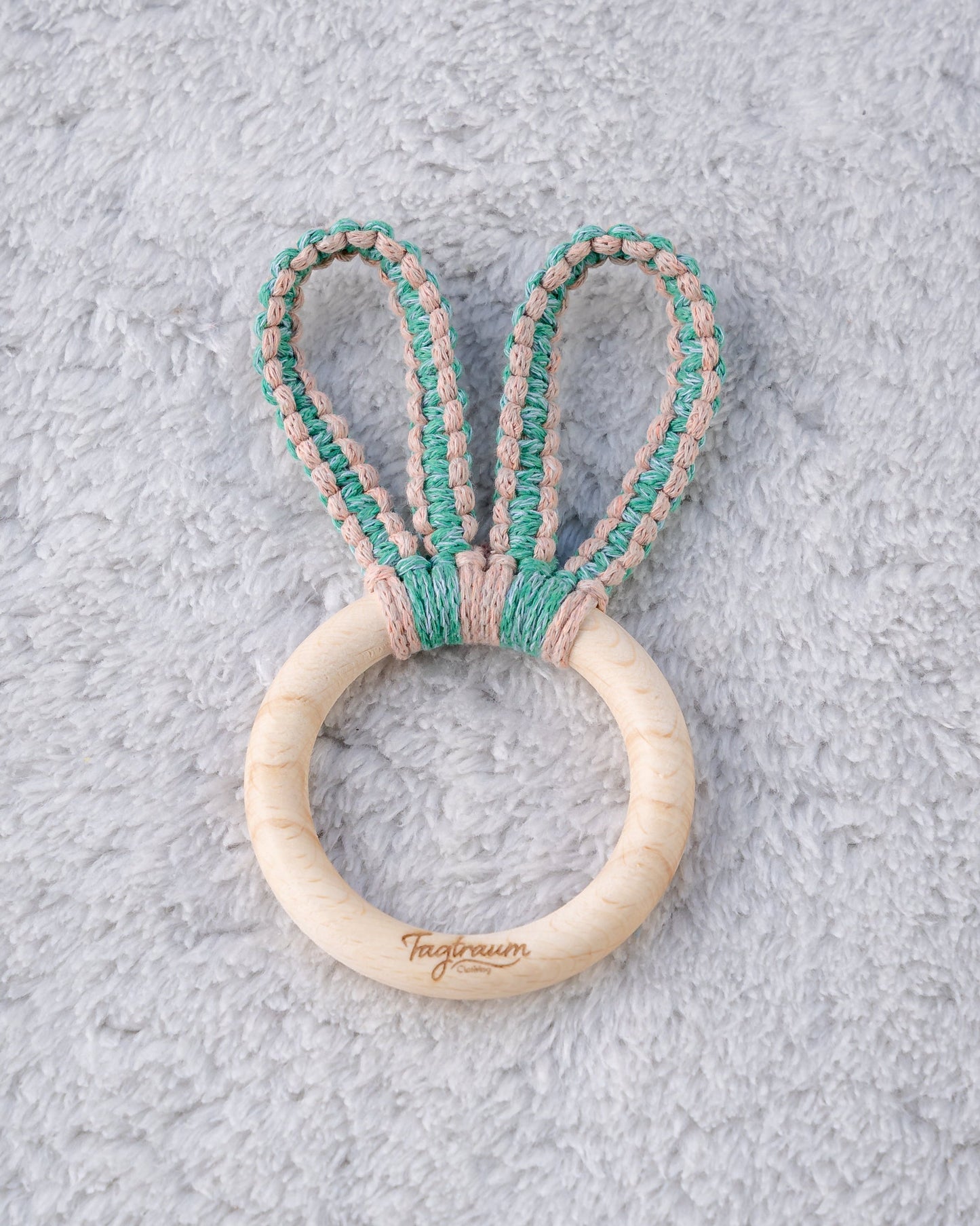 Süsser Greifling aus einem schönen Holzring mit edler Tagtraum Gravur und süssen Hasenohren aus Makramee Garn geknüpft, in Grün und Lachsrosa. Frei von Schadstoffen und aus umweltfreundlichen, nachhaltigen Materialien. Handgefertigt in der Schweiz von Tagtraum Clothing.