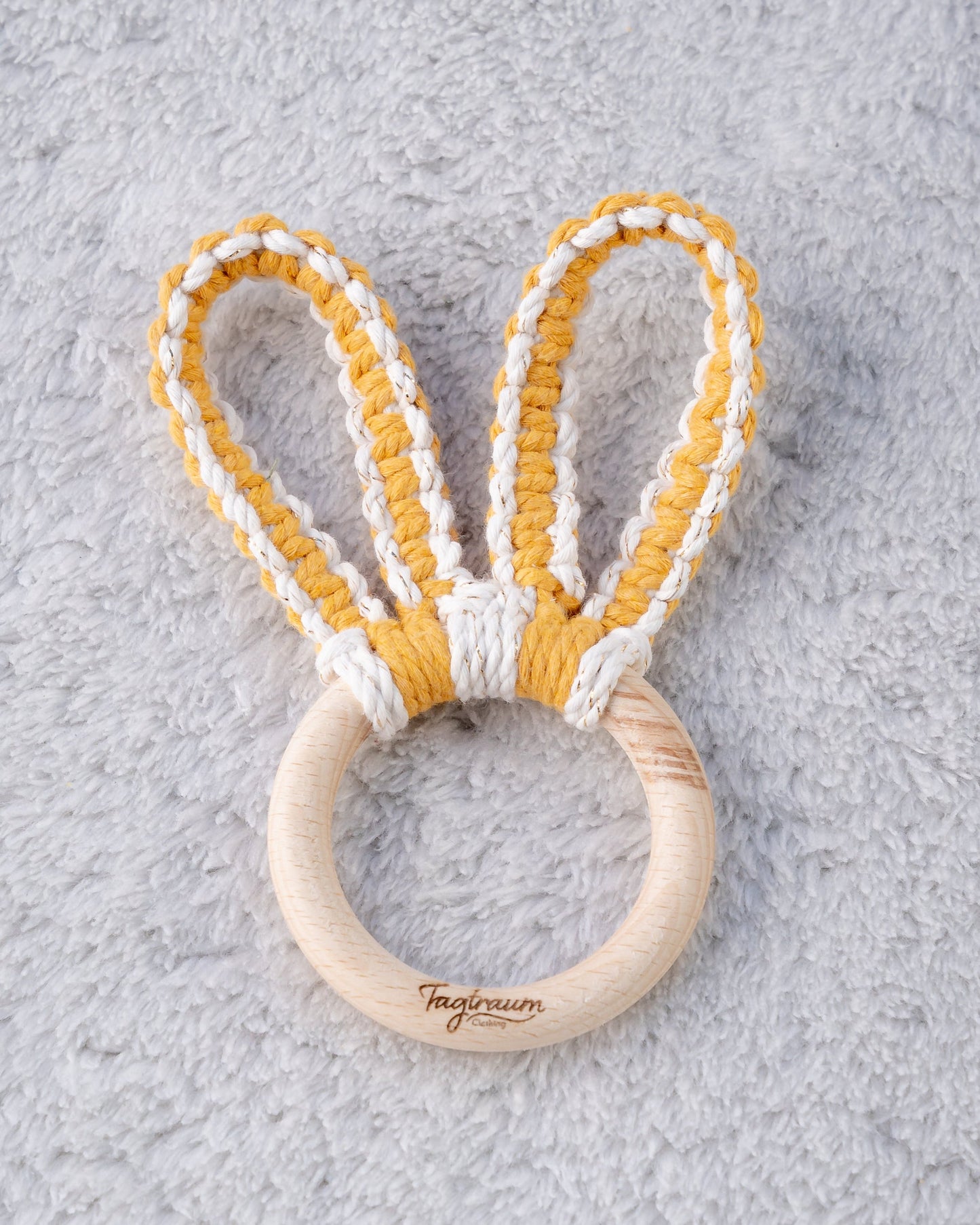 Süsser Hasenohren Beissring für Babys aus einem schönen Holzring mit edler Tagtraum Gravur und süssen Öhrchen geknüpft aus Makramee Garn in sonnigem Gelb und Ecru mit Goldeinschlüssen. Handgefertigt von Tagtraum Clothing in der Schweiz