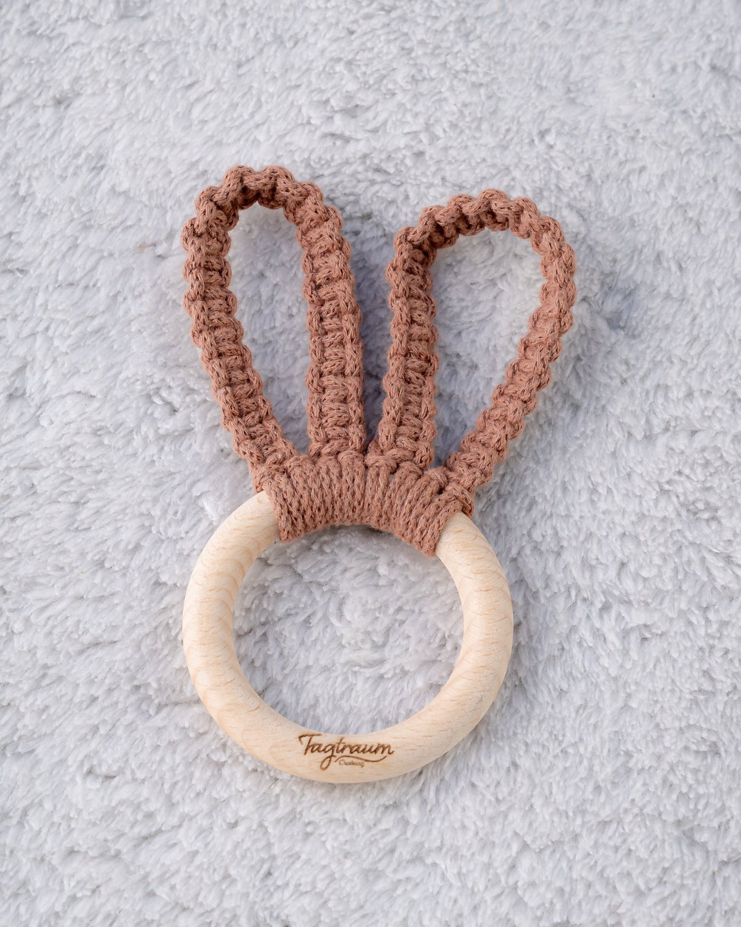 Süsser Hasenohren Greifling für Babys, aus einem schönen Holzring mit edler Tagtraum Gravur und geknüpften Hasenohren aus Makramee Garn in schönem Braun. Handgefertigt in der Schweiz von Tagtraum Clothing; schadstofffrei und umweltfreundlich.