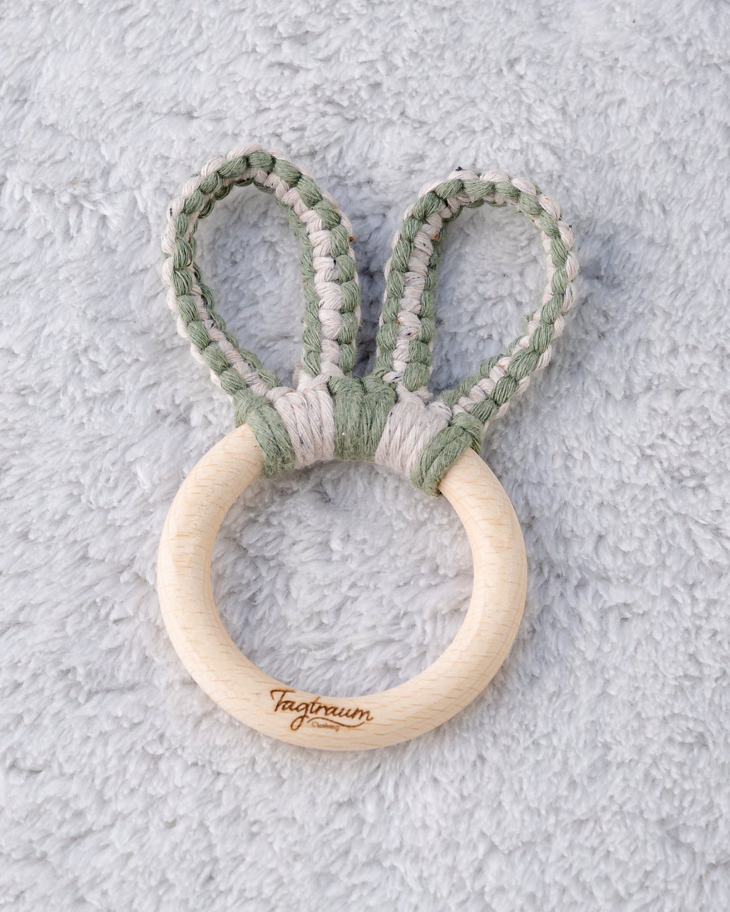 Süsser Greifling für Babys, mit einem angenehmen Holzring mit edler Tagtraum Gravur und geknüpften Hasenohren aus Makramee Garn in Eukalyptus Grün und Beige (gesprenkelt)