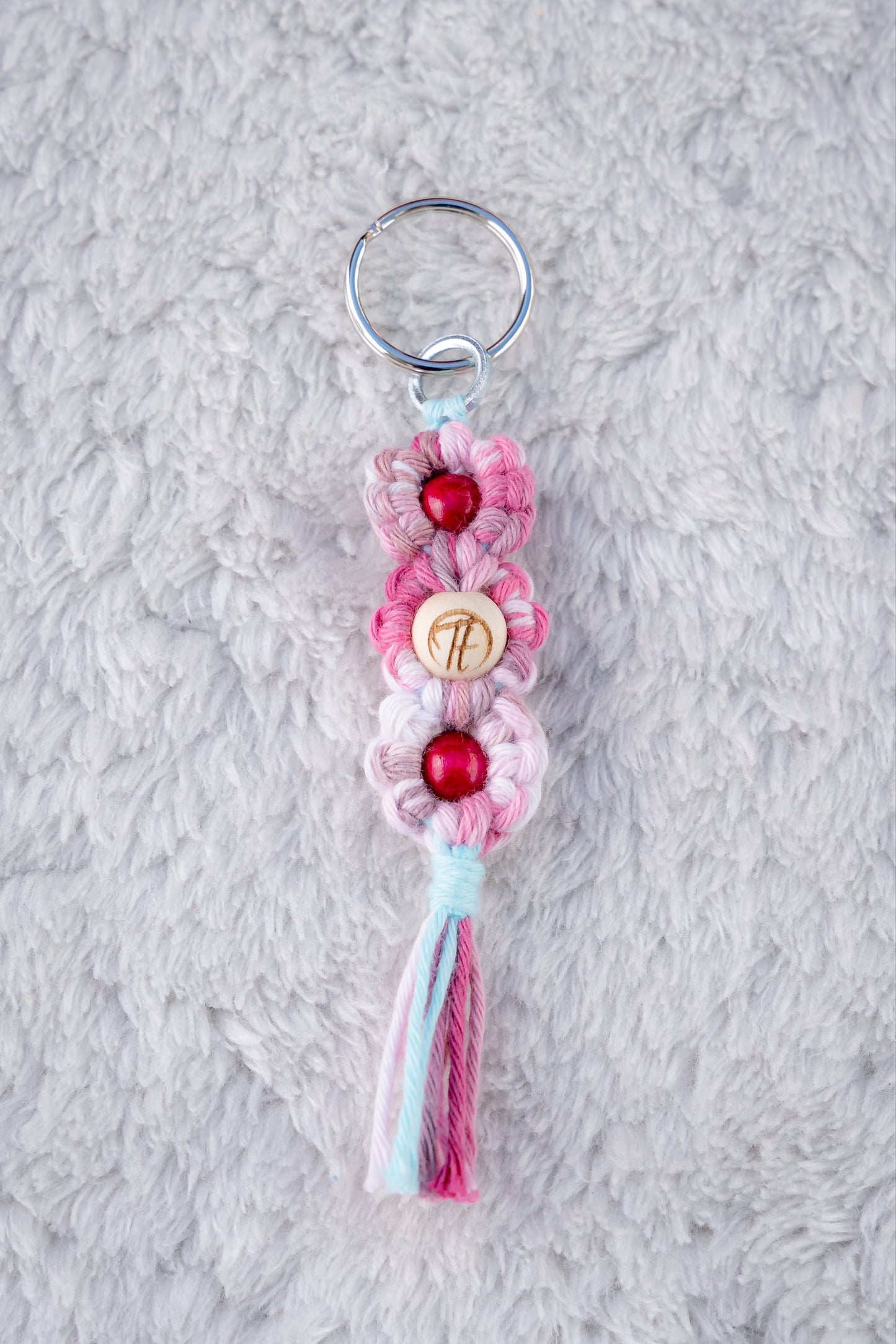 Schöner Makramee Schlüsselanhänger geknüpft aus einem rosa/pinken Garnmix, mit drei Holzperlen, eine davon versehen mit unserem Tagtraum Logo, die anderen in einem kräftigen Pink. Umweltfreundlich, nachhaltig und handgefertigt von uns in der Schweiz.