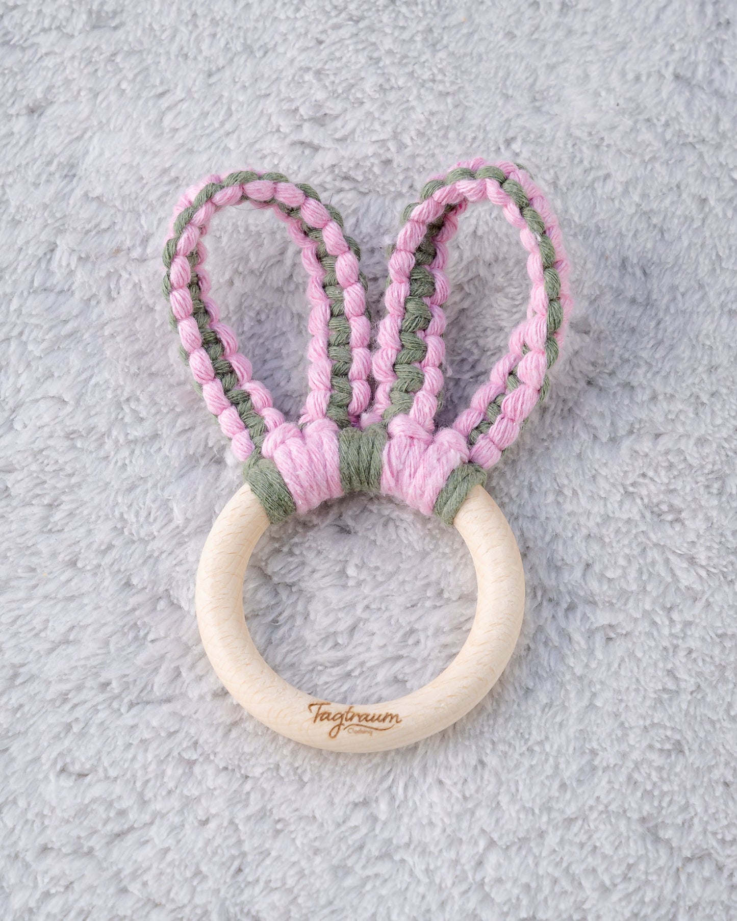 Süsser Hasenohren Greifling aus einem schönen Holzring mit elder Tagtraum Gravur und süssen Öhrchen geknüpft aus Makramee Garn in zartem Rosa und Eukalyptus Grün. Handgefertigt in der Schweiz von Tagtraum Clothing.