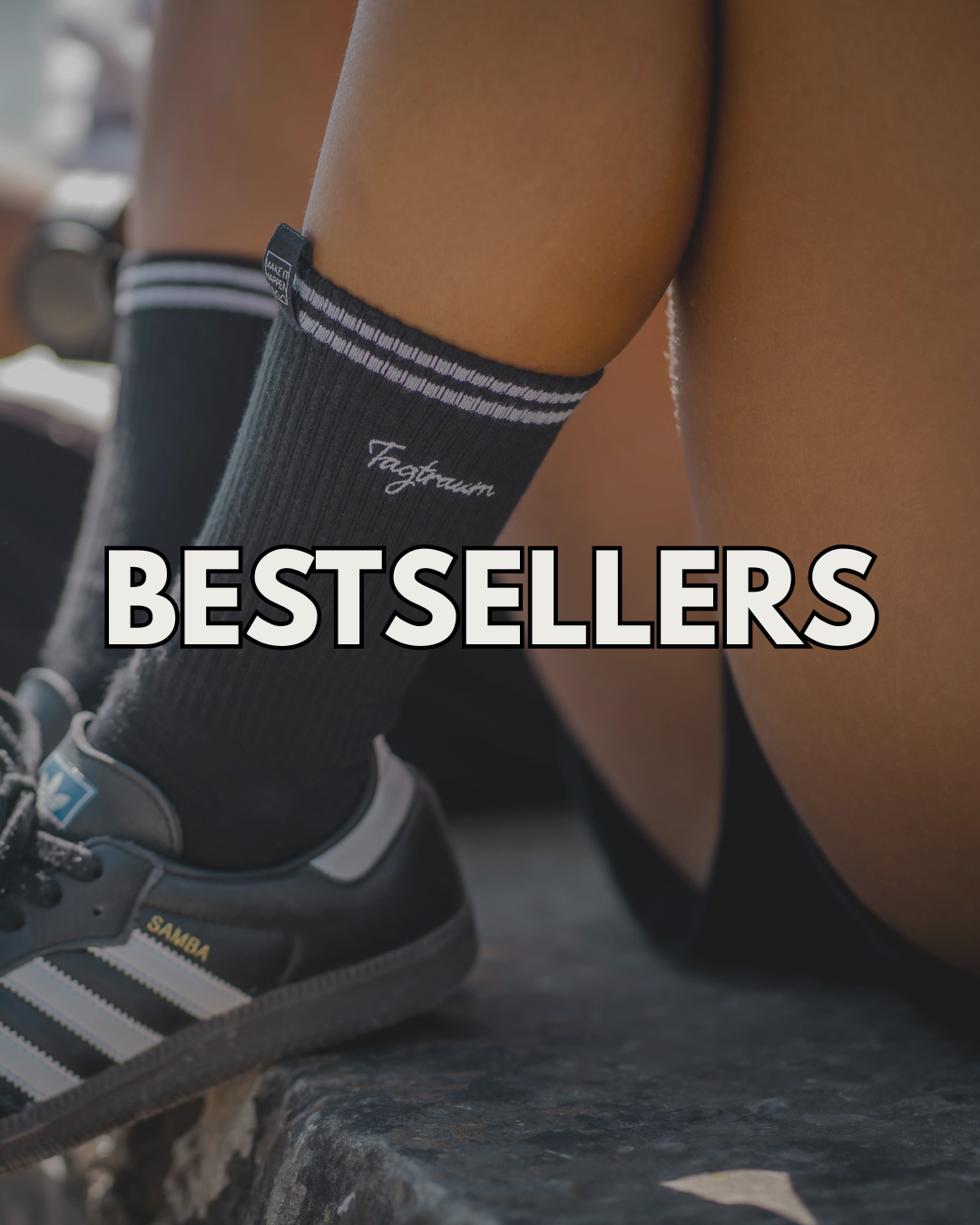 Zwei junge Frauen in einer Schneelandschaft lachen, mit Schlittschuhen, beide tragen ein Tagtraum Beanie (schwarz und graublau), ein schwarzes Tagtraum Unisex Shirt und Tagtraum Shorts