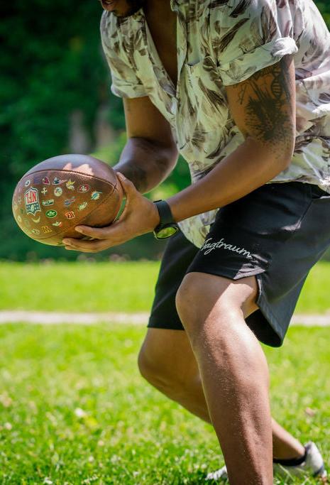 Schwarze Bio Baumwoll Shorts, getragen von einem männlichen Model, welches draussen auf einer Wiese American Football spielt. Er fängt gerade den Football und ist in Bewegung. Das Gesicht sieht man knapp nicht.