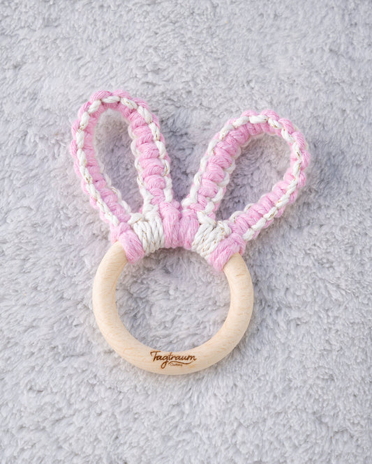 Süsser Hasenohren Greifling für Babys aus einem schönem Holzring mit edler Tagtraum Gravur und süssen Hasenöhrchen geknüpft aus Makramee Garn in zartem Rosa und Ecru mit Gold Einschlüssen. Handgefertigt in der Schweiz von Tagtraum Clothing.