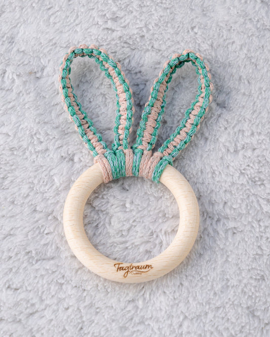 Süsser Hasenohren Greifling für Babys, aus einem schönen Holzring mit edler Tagtraum Gravur und Hasenöhrchen geknüpft aus Makramee Garn in Lachsrosa und Grün. Handgeknüpft von Tagtraum Clothing in der Schweiz