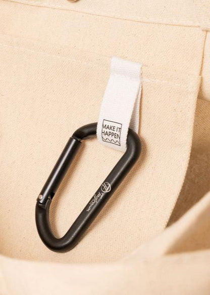 Der kleine Aluminium Karabiner an der "Make it happen"-Lasche im Bio-Baumwoll Shopper befestigt