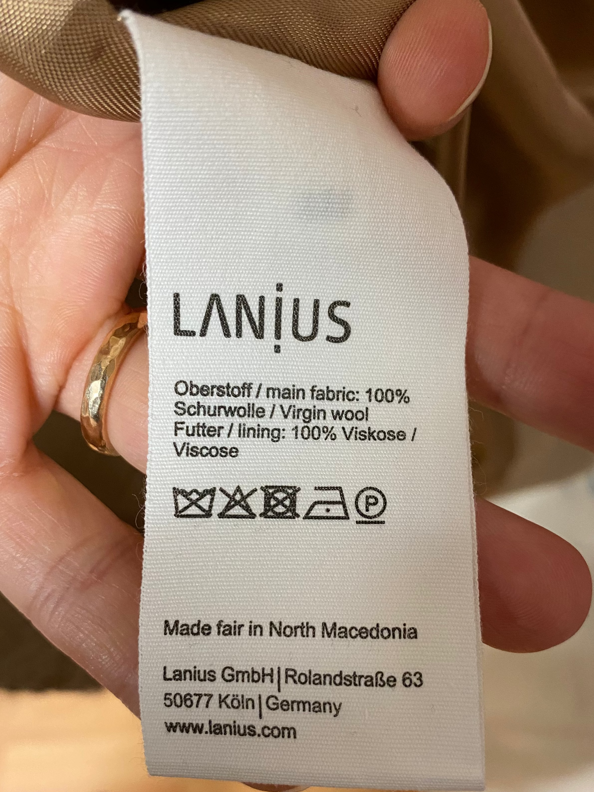 Etikett eines Wollmantels von der Marke Lanius; mit Materialangabe, Waschsymbolen und Herstellungsland