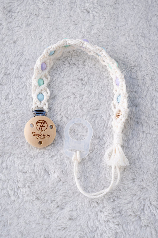 Schöne Schnullerkette aus weissem Garn mit babyblauen,türkisen und lila Holzperlen, einem hochwertigen Schnullerclip aus Holz, und einem Adapter für MAM Schnuller. Auf dem Holzclip befindet sich eine dle Tagtraum Cothing Gravur mit Logo. Die Schnullerketten werden handgefertigt von Tagtraum Clothing in der Schweiz.