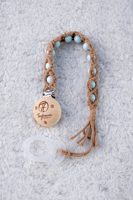 Schöne Schnullerkette aus braunem Garn mit babyblauen Holzperlen, einem hochwertigen Schnullerclip aus Holz, und einem Adapter für MAM Schnuller. Auf dem Holzclip befindet sich eine dle Tagtraum Cothing Gravur mit Logo. Die Schnullerketten werden handgefertigt von Tagtraum Clothing in der Schweiz.