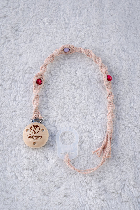 Schöne Schnullerkette aus lachsrosanem Garn mit pinken und lila Holzperlen, einem hochwertigen Schnullerclip aus Holz, und einem Adapter für MAM Schnuller. Auf dem Holzclip befindet sich eine dle Tagtraum Cothing Gravur mit Logo. Die Schnullerketten werden handgefertigt von Tagtraum Clothing in der Schweiz.