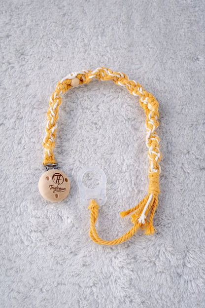 Schöne Schnullerkette aus sonnengelbem und weissem Garn mit natur Holzperlen, einem hochwertigen Schnullerclip aus Holz, und einem Adapter für MAM Schnuller. Auf dem Holzclip befindet sich eine dle Tagtraum Cothing Gravur mit Logo. Die Schnullerketten werden handgefertigt von Tagtraum Clothing in der Schweiz.