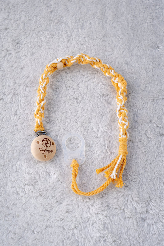 Schöne Schnullerkette aus sonnengelbem und weissem Garn mit natur Holzperlen, einem hochwertigen Schnullerclip aus Holz, und einem Adapter für MAM Schnuller. Auf dem Holzclip befindet sich eine dle Tagtraum Cothing Gravur mit Logo. Die Schnullerketten werden handgefertigt von Tagtraum Clothing in der Schweiz.