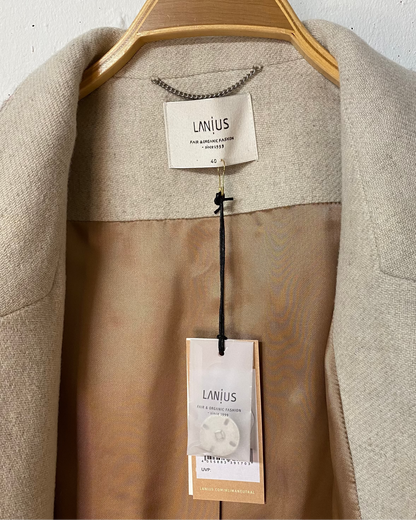 Innenseite eines schönen, kuschelig warmen Wollmantel von Lanius. Man sieht den Hang Tag mit Ersatzknopf, sowie das Label, die Aufhängelasche und die Grössenangabe. 